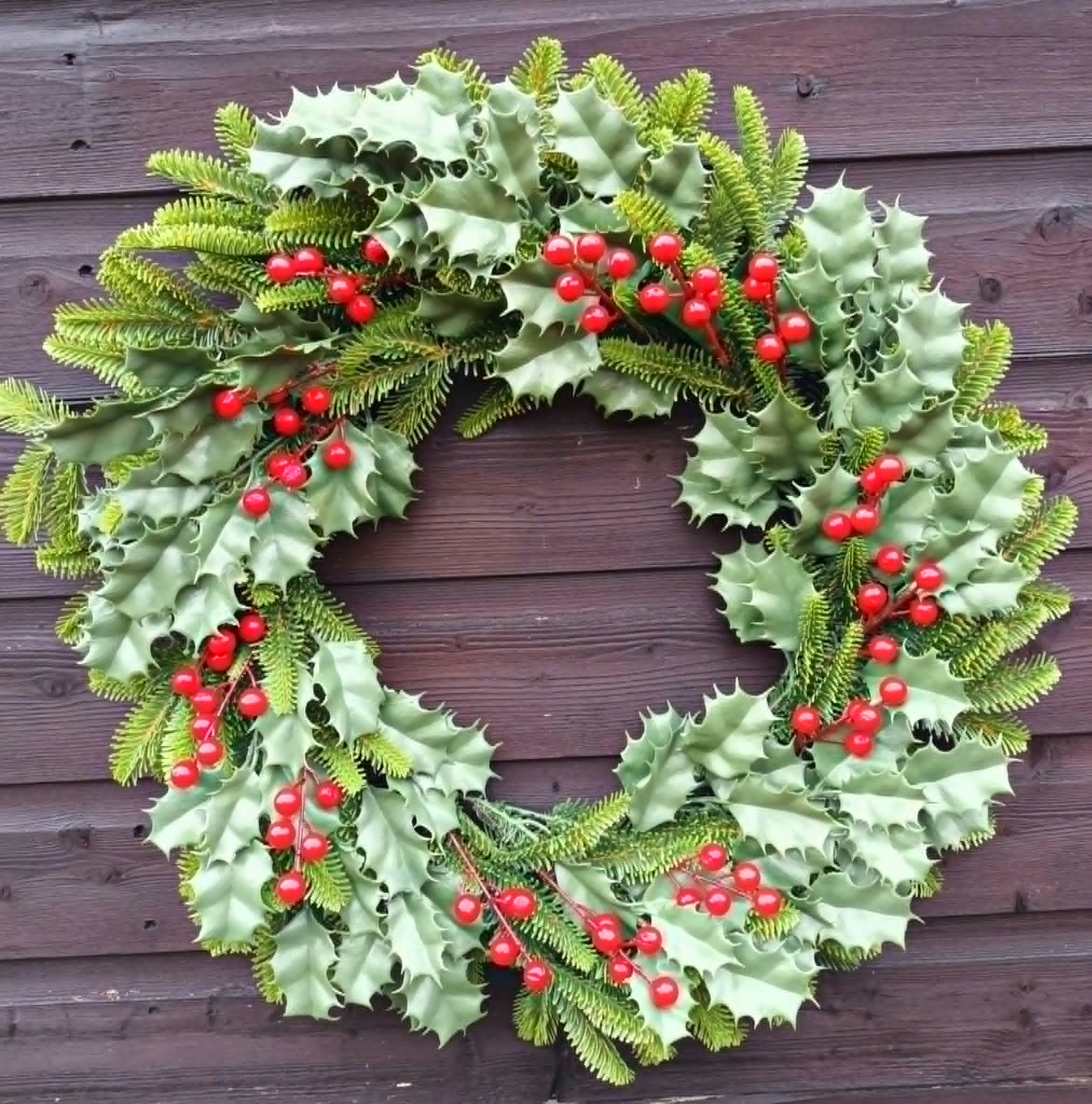 Robust wreath with green holly and spruce foliage and clusters of red berries