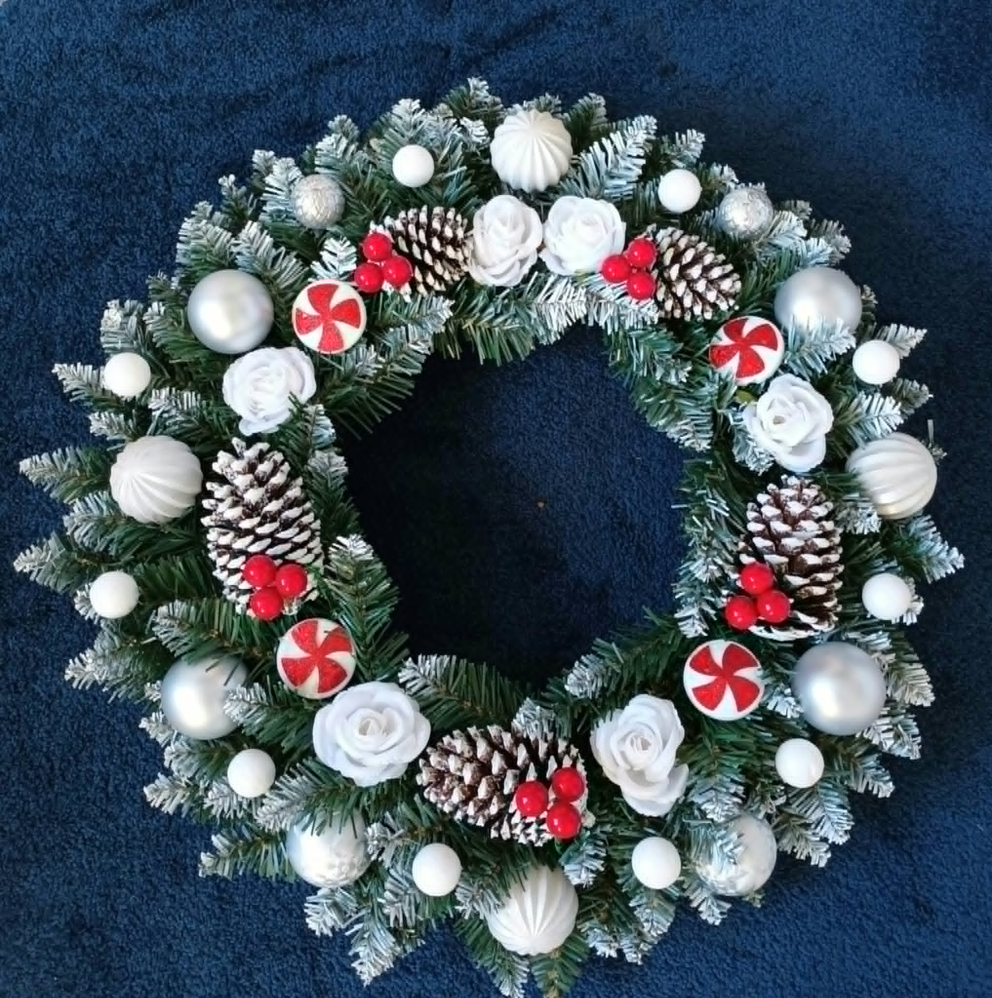 Silver and white Wonderland wreath with frosted greenery, white roses, silver baubles, pine cones and red accents
